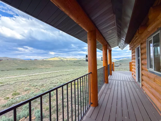 Covered deck featuring wood-finish flooring, log pillars, and black metal railings