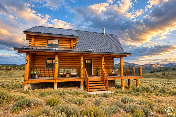Log cabin exterior with a metal roof, prominent front porch, and wood railing