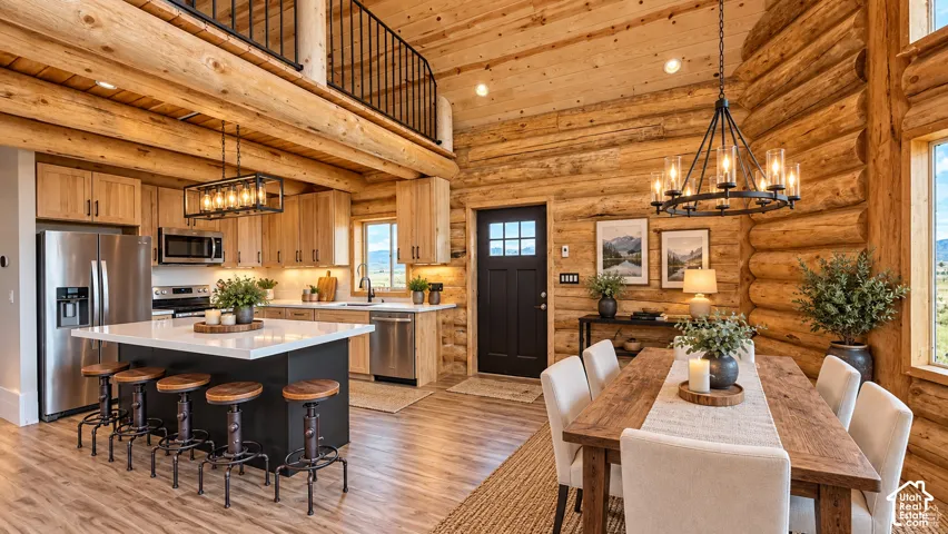Open concept living space with wood-finish flooring, exposed log walls, and a lofted ceiling
