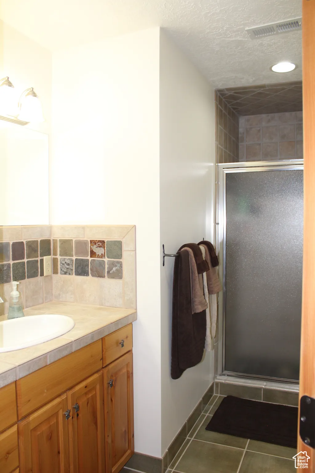 Full bathroom with vanity, a stall shower, tile patterned flooring, decorative backsplash, and baseboards