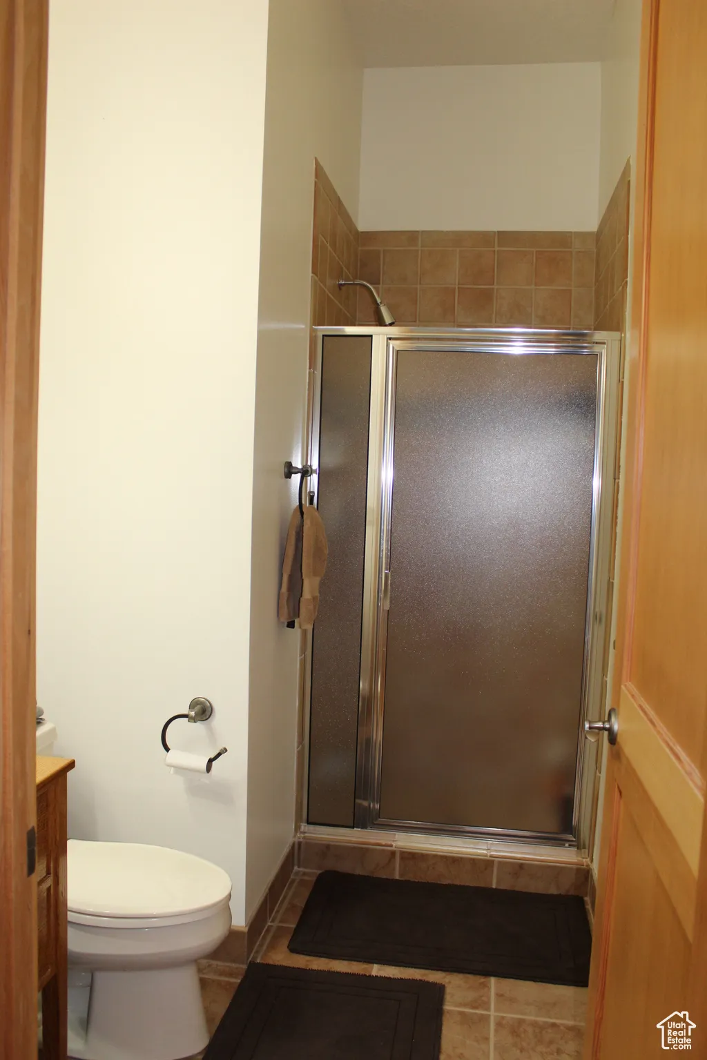 Bathroom featuring a shower stall, vanity, toilet, and tile patterned flooring
