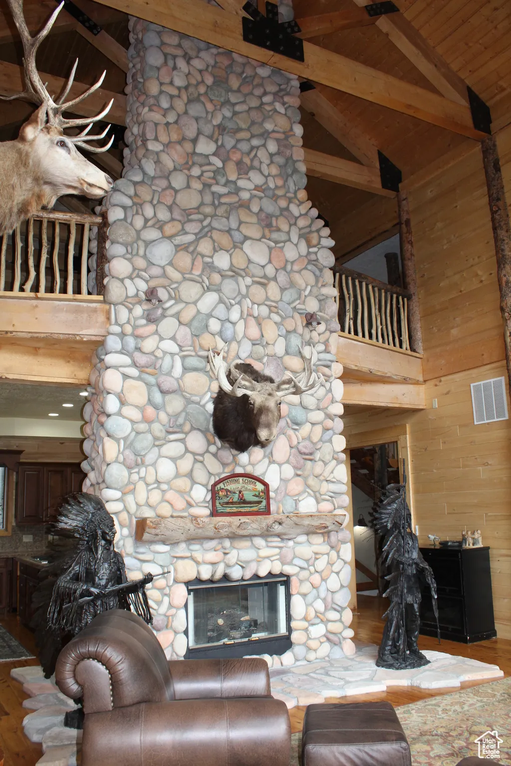 Living room with a fireplace, high vaulted ceiling, wood ceiling with exposed beams, wood walls, and wood finished floors