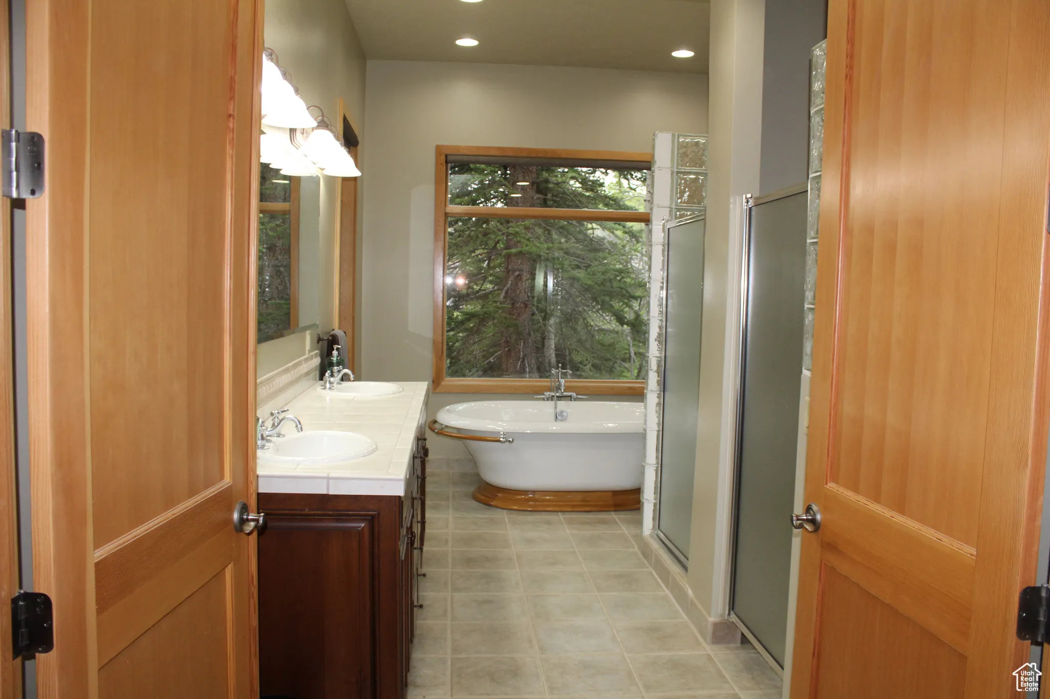 Full bathroom featuring double vanity, a freestanding bath, and recessed lighting