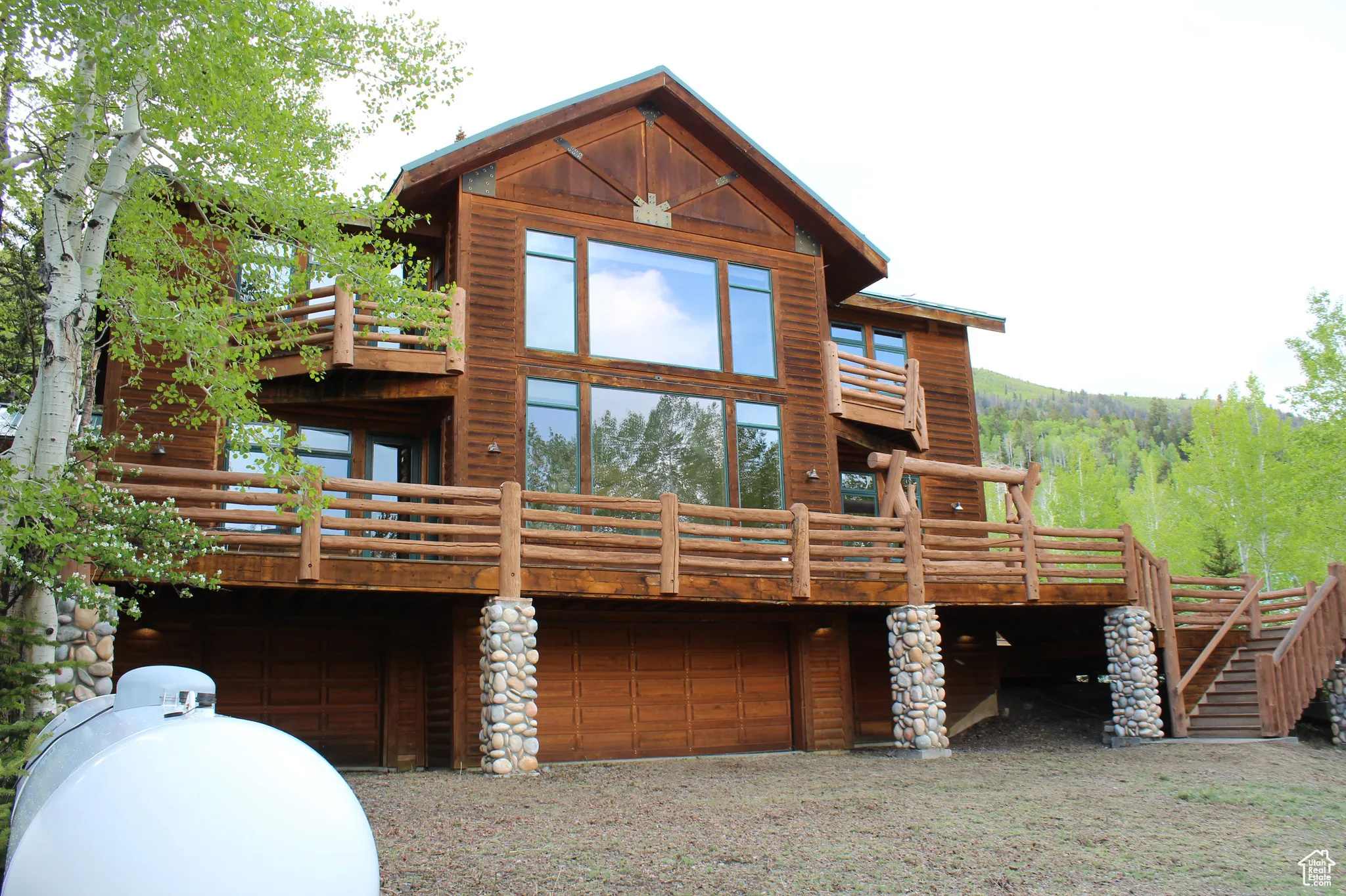 Back of house with an attached garage, a wooden deck, and gravel driveway