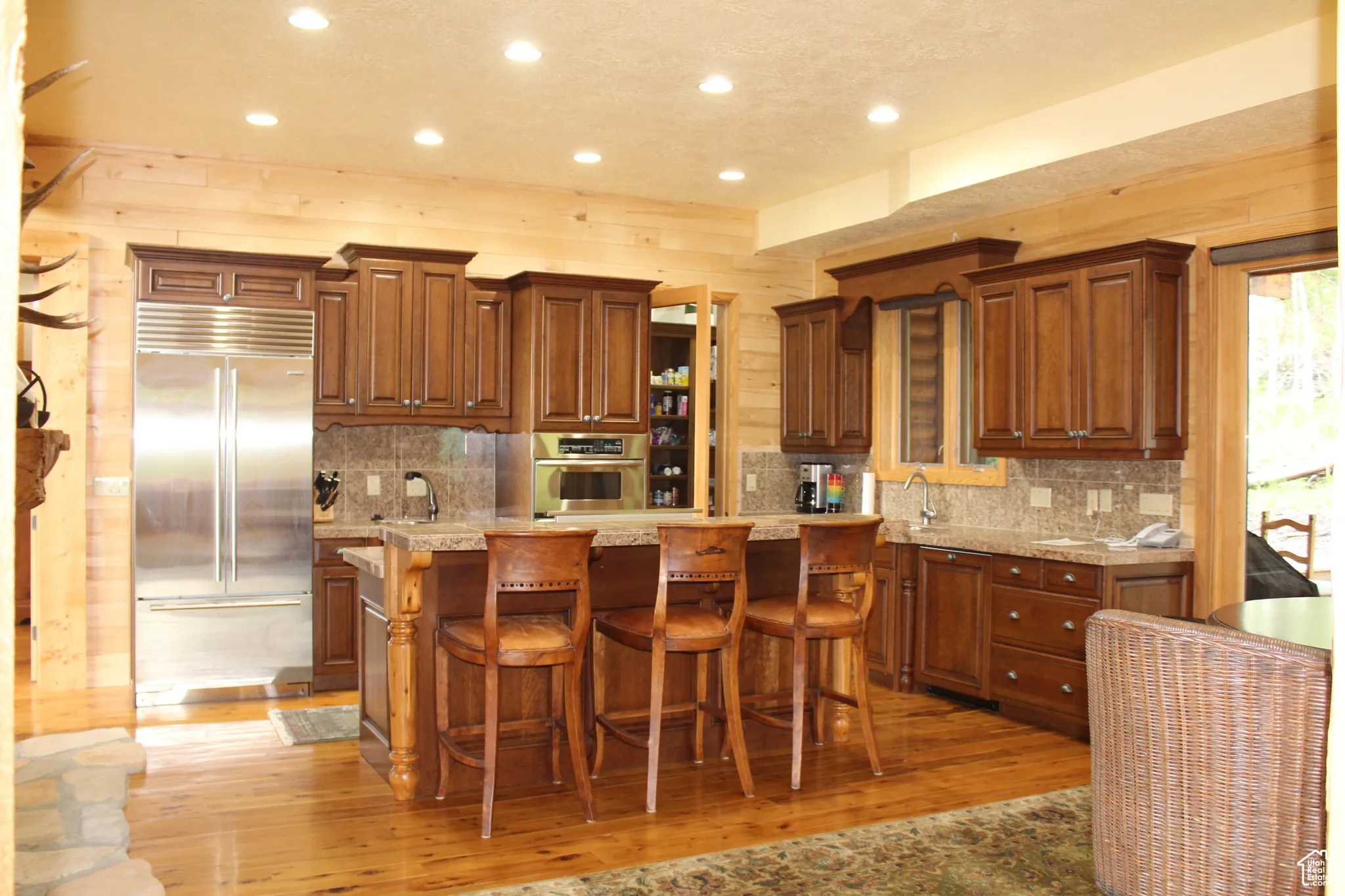 Kitchen featuring stainless steel appliances, light wood-type flooring, recessed lighting, tasteful backsplash, and a kitchen bar