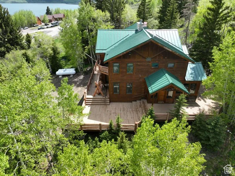 Back of property with a standing seam roof, metal roof, a chimney, and a deck with water view