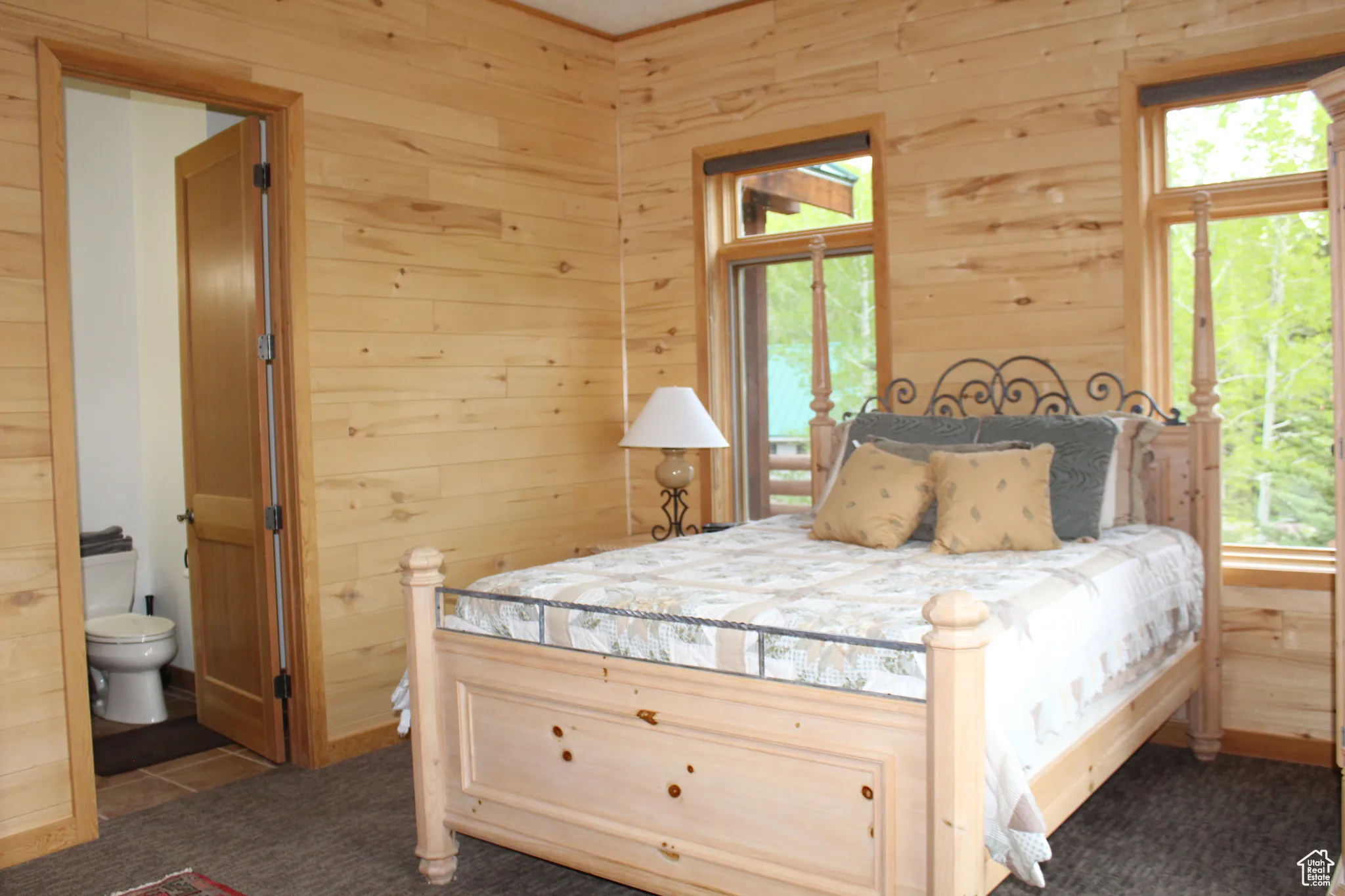 Bedroom with wood walls, ensuite bath, and carpet flooring