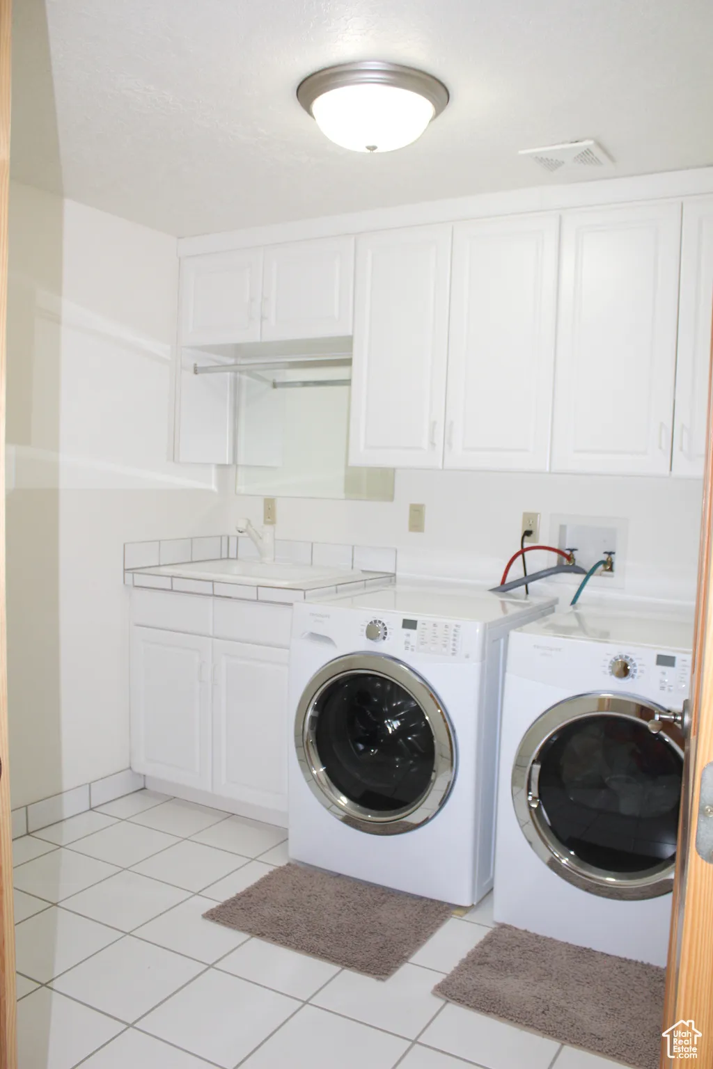 Washroom with washer and clothes dryer, cabinet space, and light tile patterned flooring