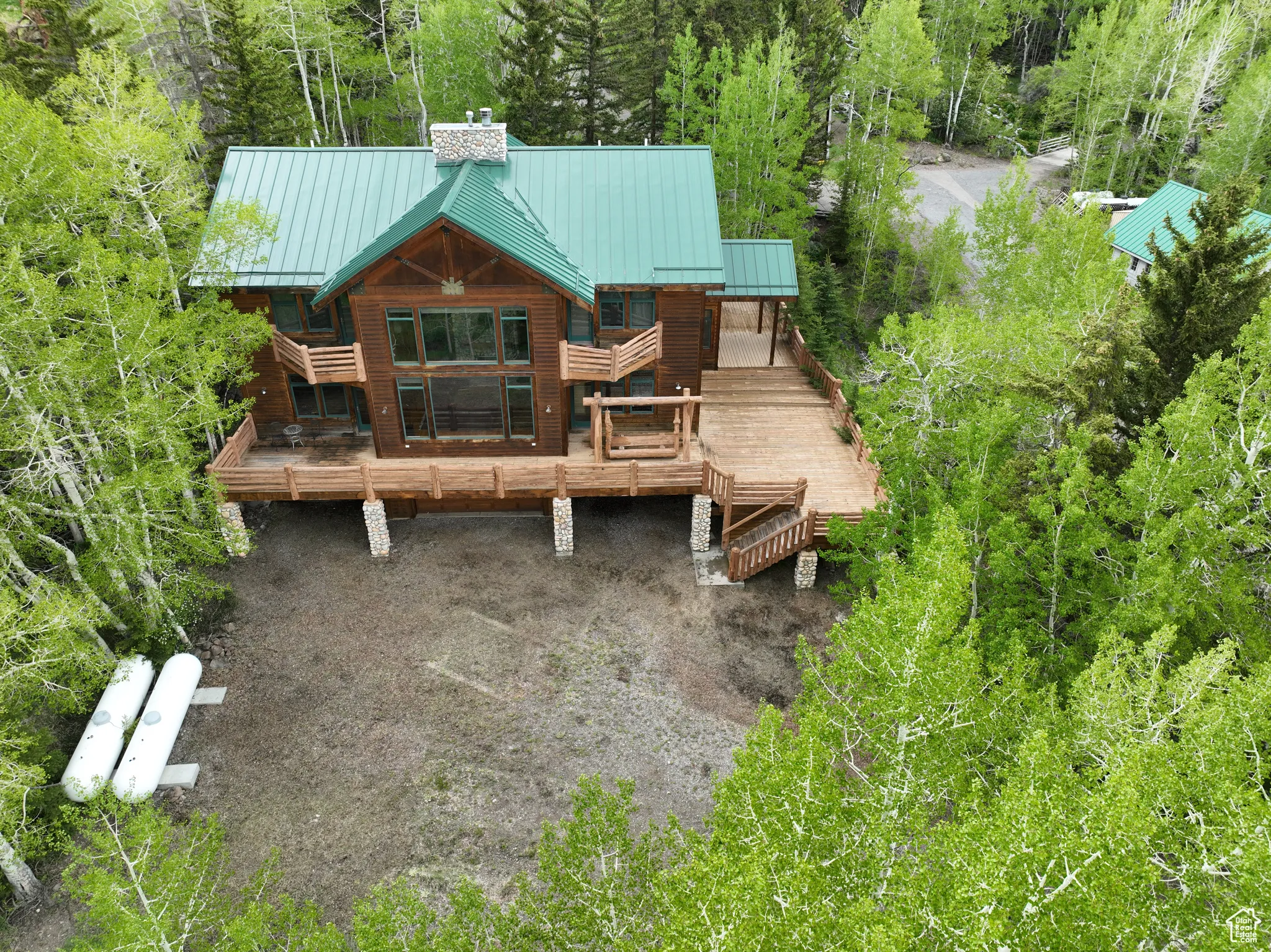 Rear view of property featuring a chimney, a standing seam roof, stairs, and metal roof