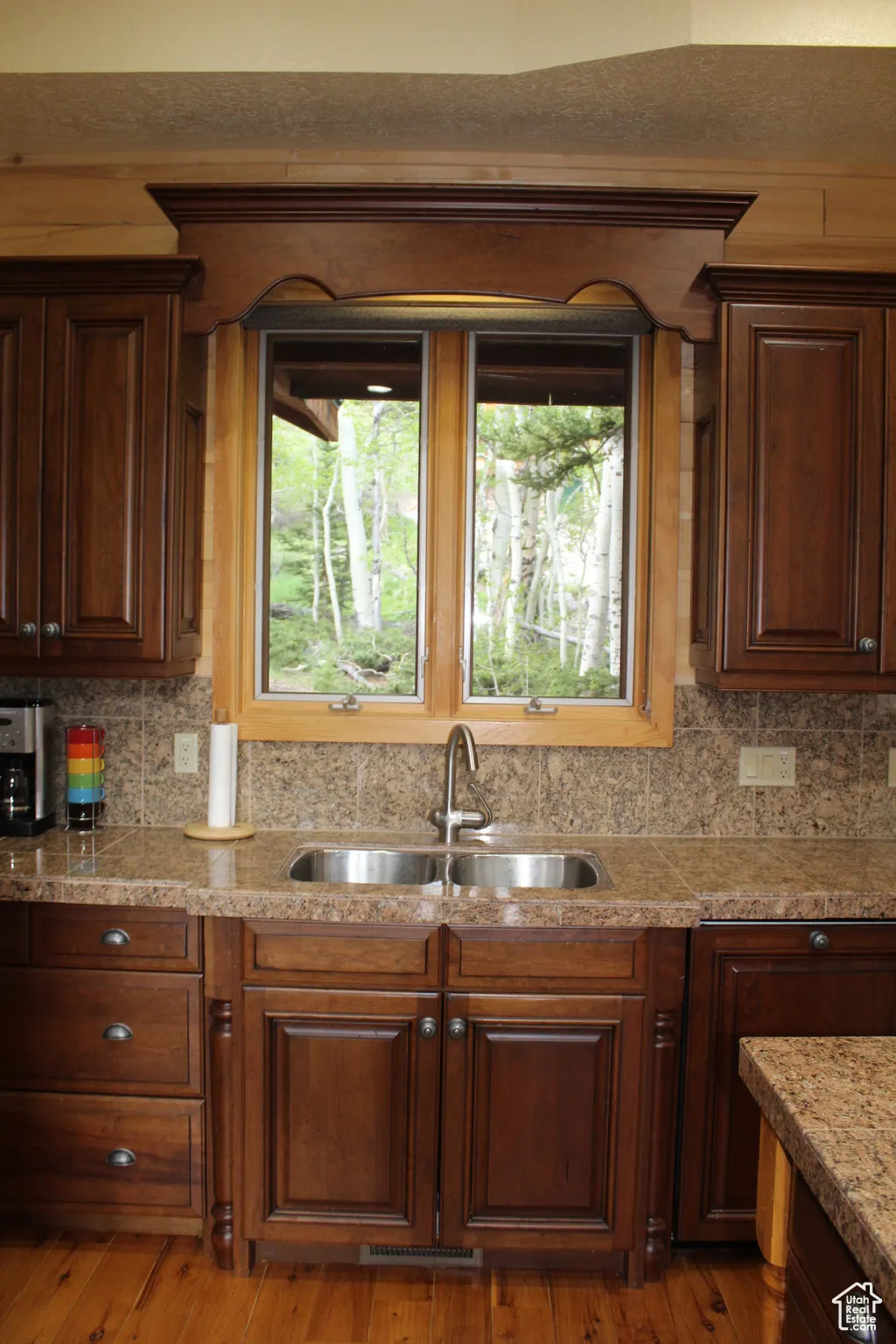 Kitchen featuring a sink, light countertops, decorative backsplash, and light wood-style floors