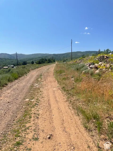 View of dirt / gravel road featuring a view of countryside and a mountain view