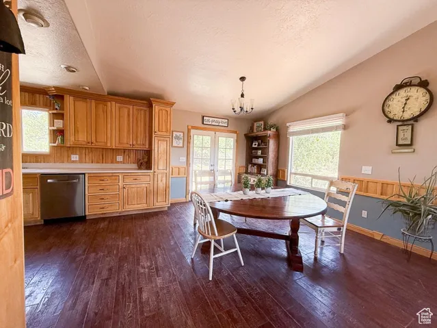 Dining space featuring vaulted ceiling, dark wood-style flooring, french doors, a textured ceiling, and a chandelier