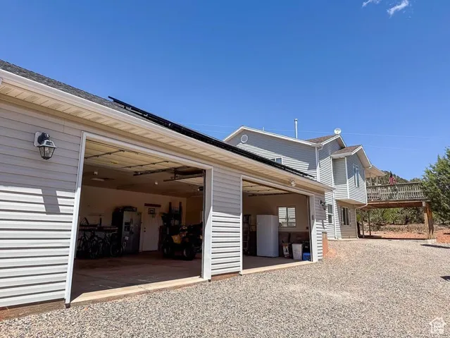 View of property exterior featuring a garage and gravel driveway