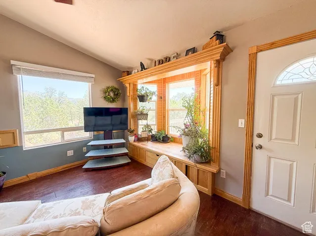 Living area with vaulted ceiling, dark wood-style floors, and baseboards
