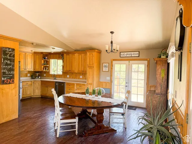 Dining room with a chandelier, dark wood-style floors, lofted ceiling, plenty of natural light, and french doors