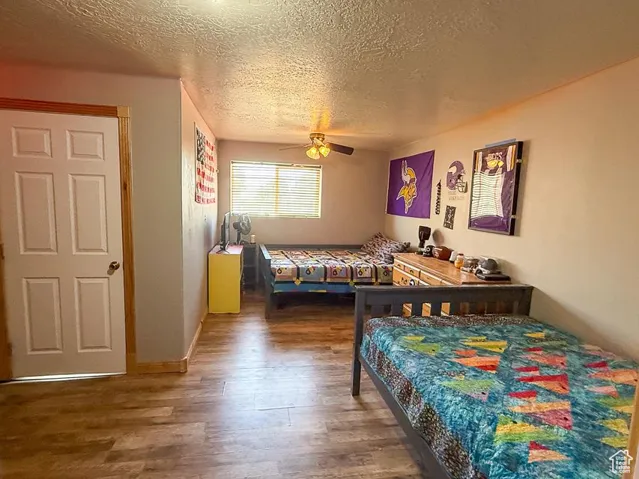 Bedroom featuring wood finished floors, a textured ceiling, and a ceiling fan