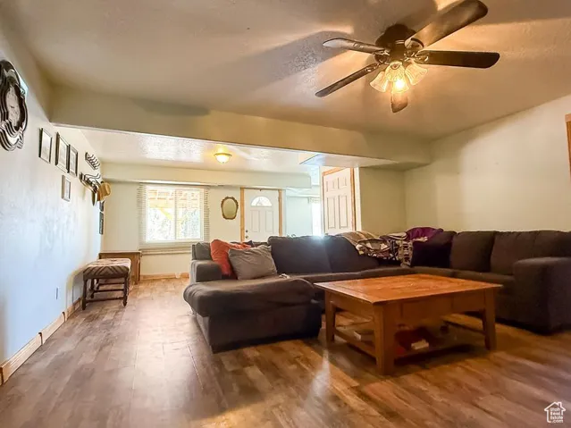 Living area with wood finished floors, a ceiling fan, and baseboards