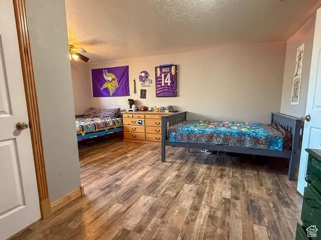 Bedroom featuring wood finished floors, a textured ceiling, and ceiling fan