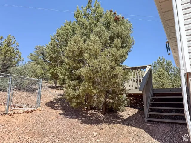 View of yard featuring a wooden deck, stairs, and a gate