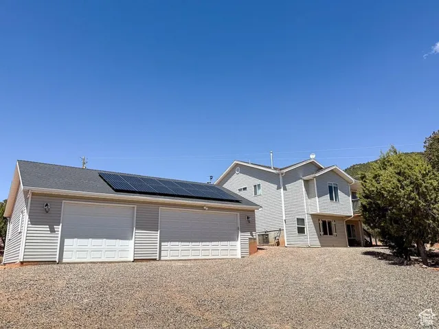View of front of home featuring a detached garage, roof mounted solar panels, and an outbuilding