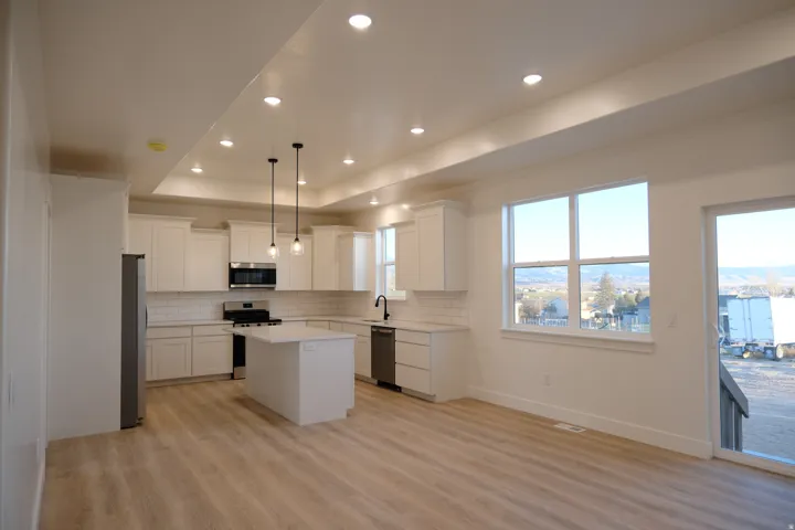 Kitchen featuring a center island, pendant lighting, white cabinets, stainless steel appliances, and recessed lighting