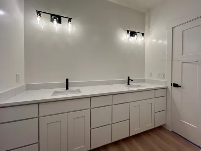 Full bathroom featuring double vanity and dark wood finished floors