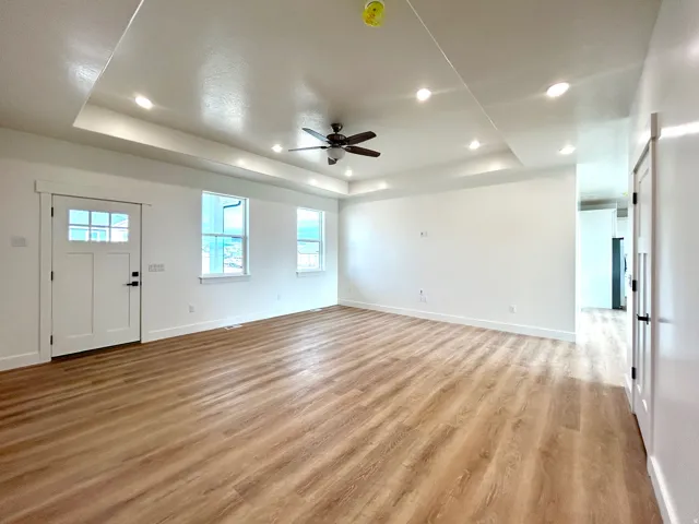 Entryway with a tray ceiling, light wood-type flooring, ceiling fan, and recessed lighting