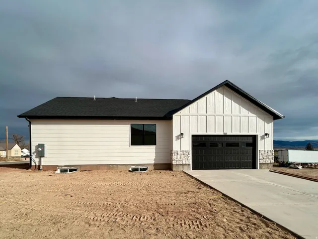 View of front facade with driveway, an attached garage, board and batten siding, and roof with shingles