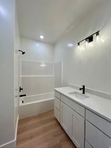 Bathroom with vanity, shower / bathtub combination, and light wood finished floors