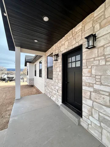 Property entrance with covered porch and stone siding