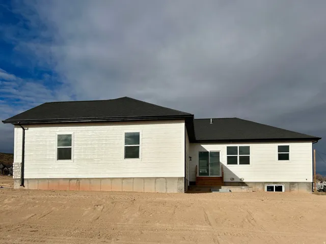 Rear view of house with entry steps and a shingled roof