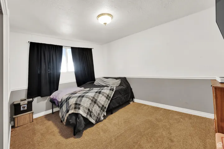 Bedroom featuring carpet, baseboards, and a textured ceiling