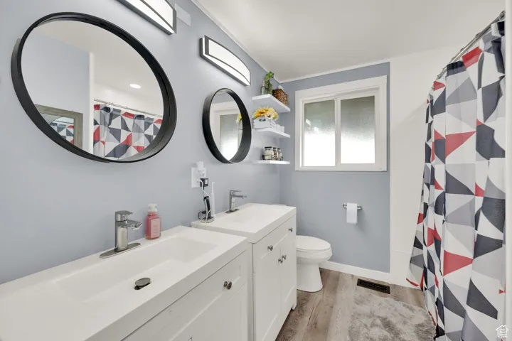 Full bath featuring wood finished floors, vanity, toilet, a shower with shower curtain, and baseboards
