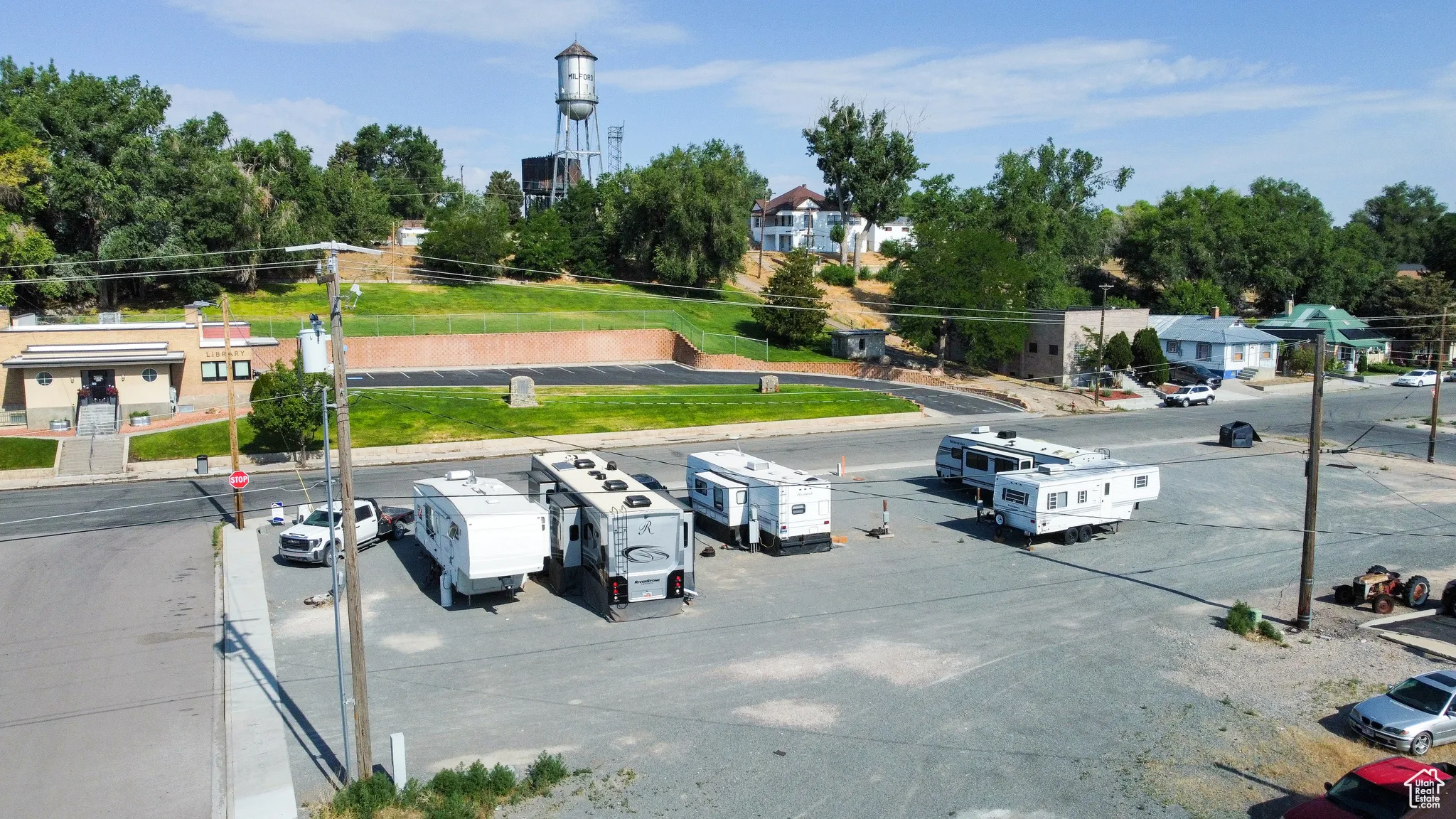 View of asphalt street with street lighting, view of wooded area, and curbs