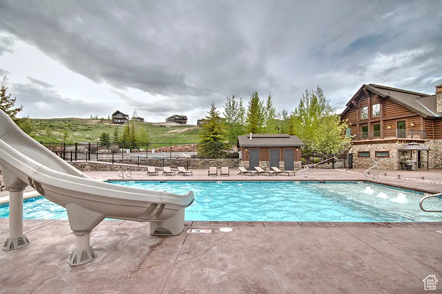 Community pool featuring a water slide and a patio