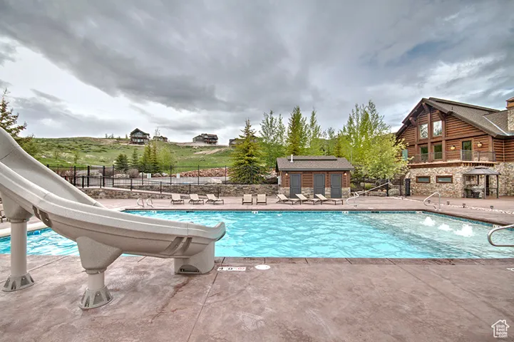 Community pool featuring a water slide and a patio