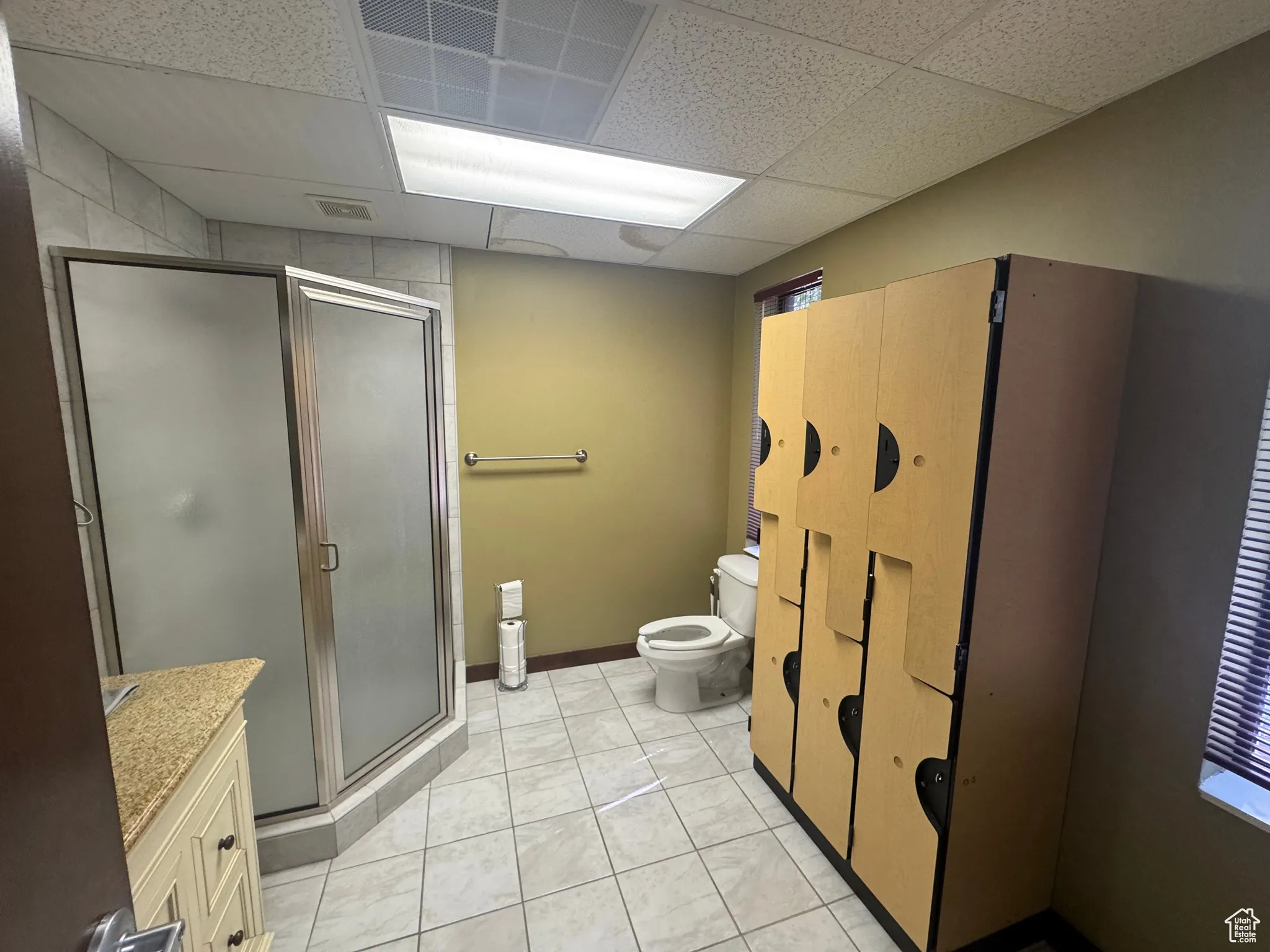 Bathroom featuring a paneled ceiling, a stall shower, vanity, and tile patterned floors