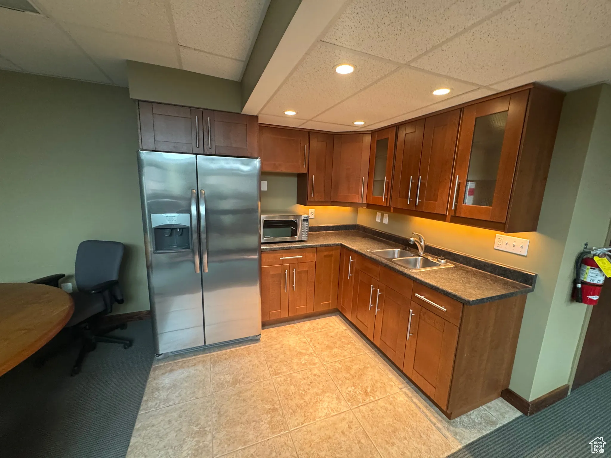 Kitchen with stainless steel appliances, recessed lighting, dark countertops, a drop ceiling, and glass insert cabinets
