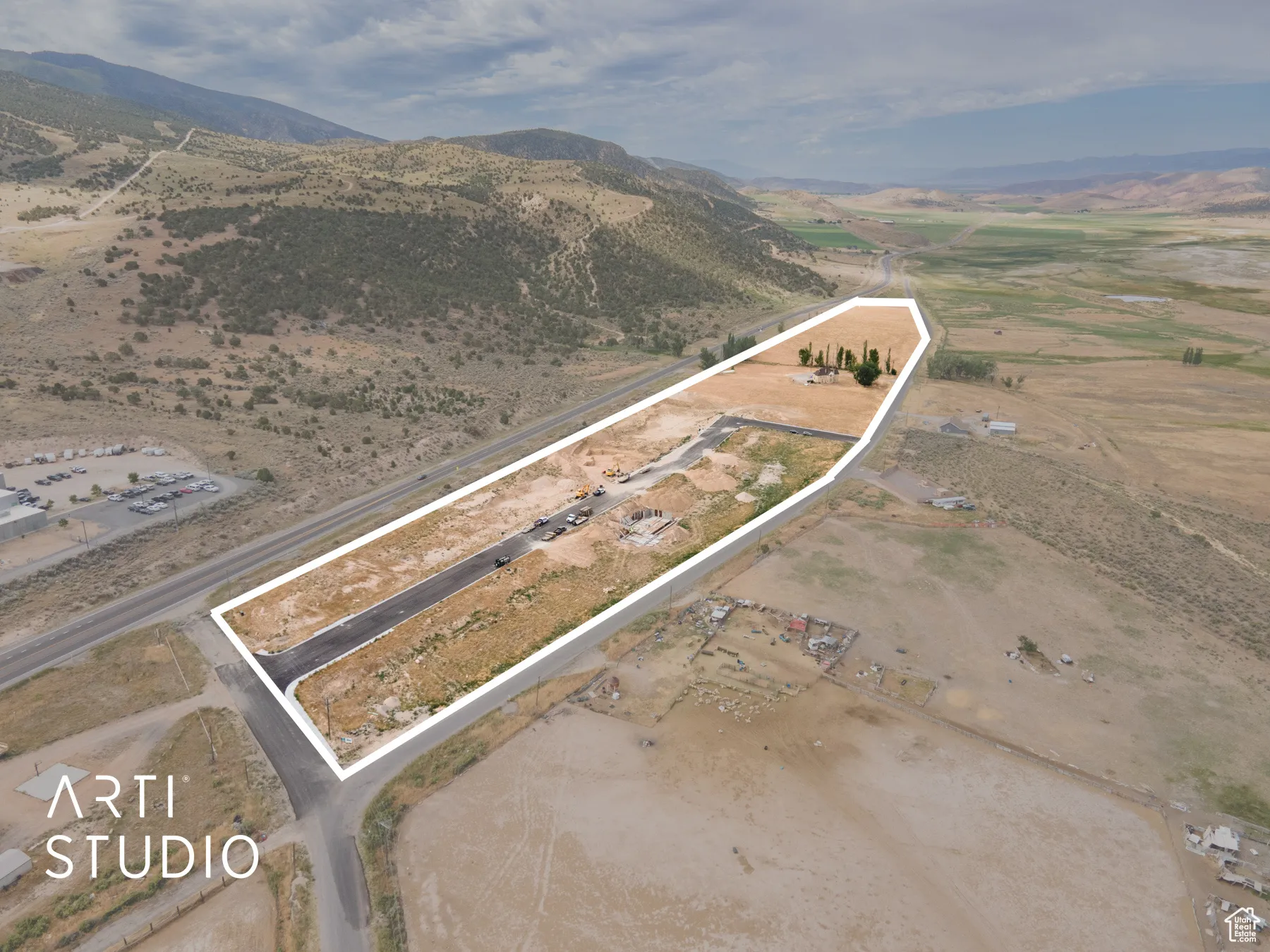 Aerial overview of property's location with property parcel outlined, rural landscape, and a mountainous background