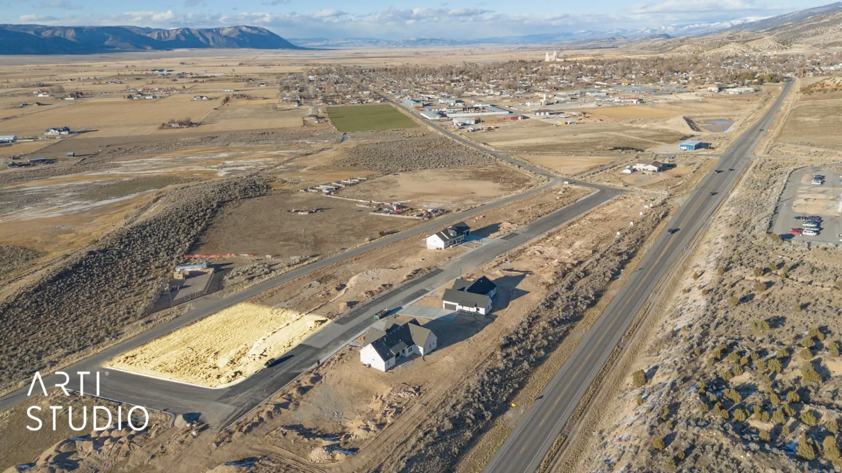 Aerial perspective showcasing newly developed residential properties alongside a paved road, with additional land available for development