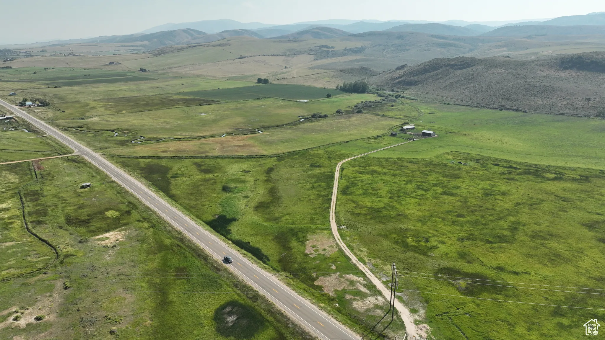 Aerial view of property and surrounding area featuring rural landscape and a mountainous background