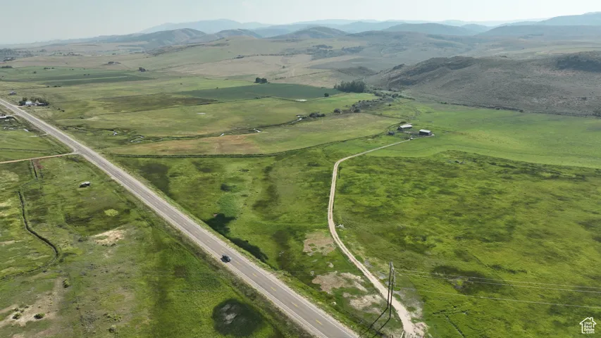 Aerial view of property and surrounding area featuring rural landscape and a mountainous background
