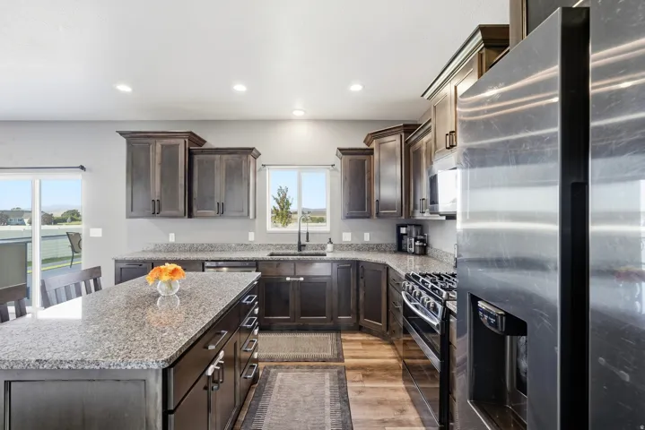 Kitchen featuring dark wood cabinetry, light-colored countertops, wood-finish flooring, a stainless steel refrigerator, and a kitchen island