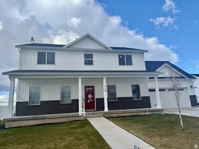 Modern farmhouse style home featuring covered porch, a front yard, brick siding, concrete driveway, and an attached garage