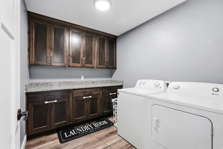 Laundry space featuring wood-finish flooring, built-in cabinetry, and a light-toned countertop