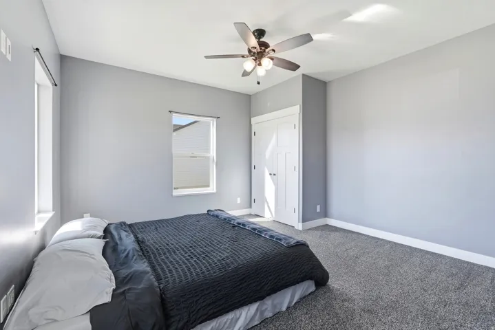 Vaulted ceiling with a ceiling fan, dual windows, and plush carpet flooring