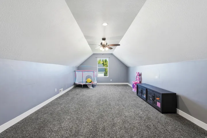 Vaulted ceiling with a ceiling fan, recessed lighting, and a window
