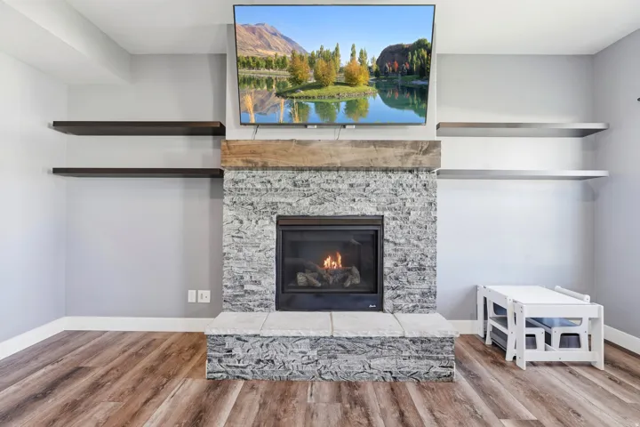 Stacked stone fireplace with a rustic wood mantel