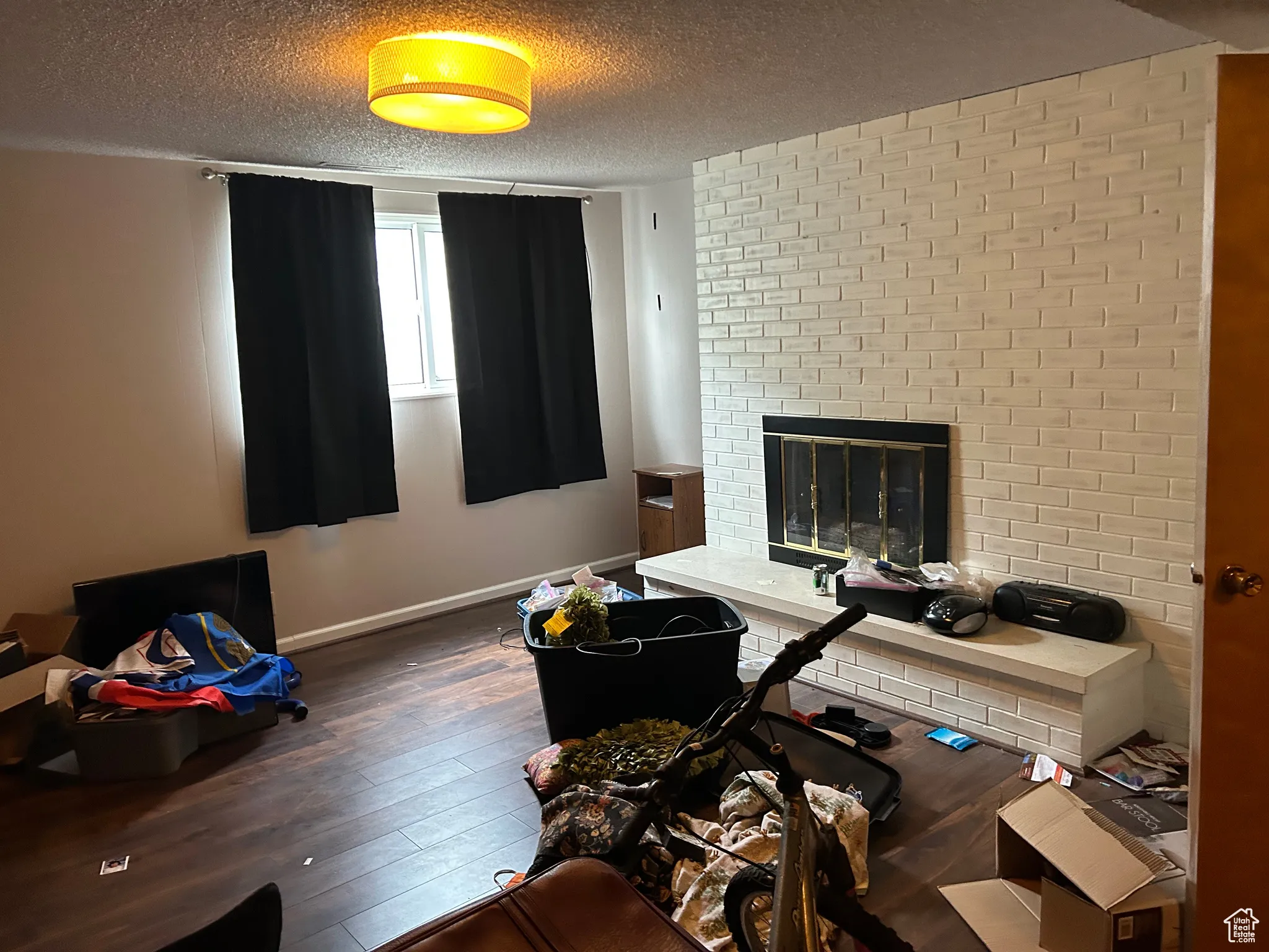 Office area featuring hardwood / wood-style flooring, a textured ceiling, baseboards, and a brick fireplace
