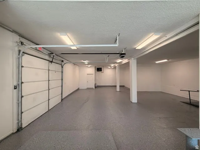 Expansive interior space featuring a large overhead door, multiple support columns, built-in shelving, and extensive overhead lighting